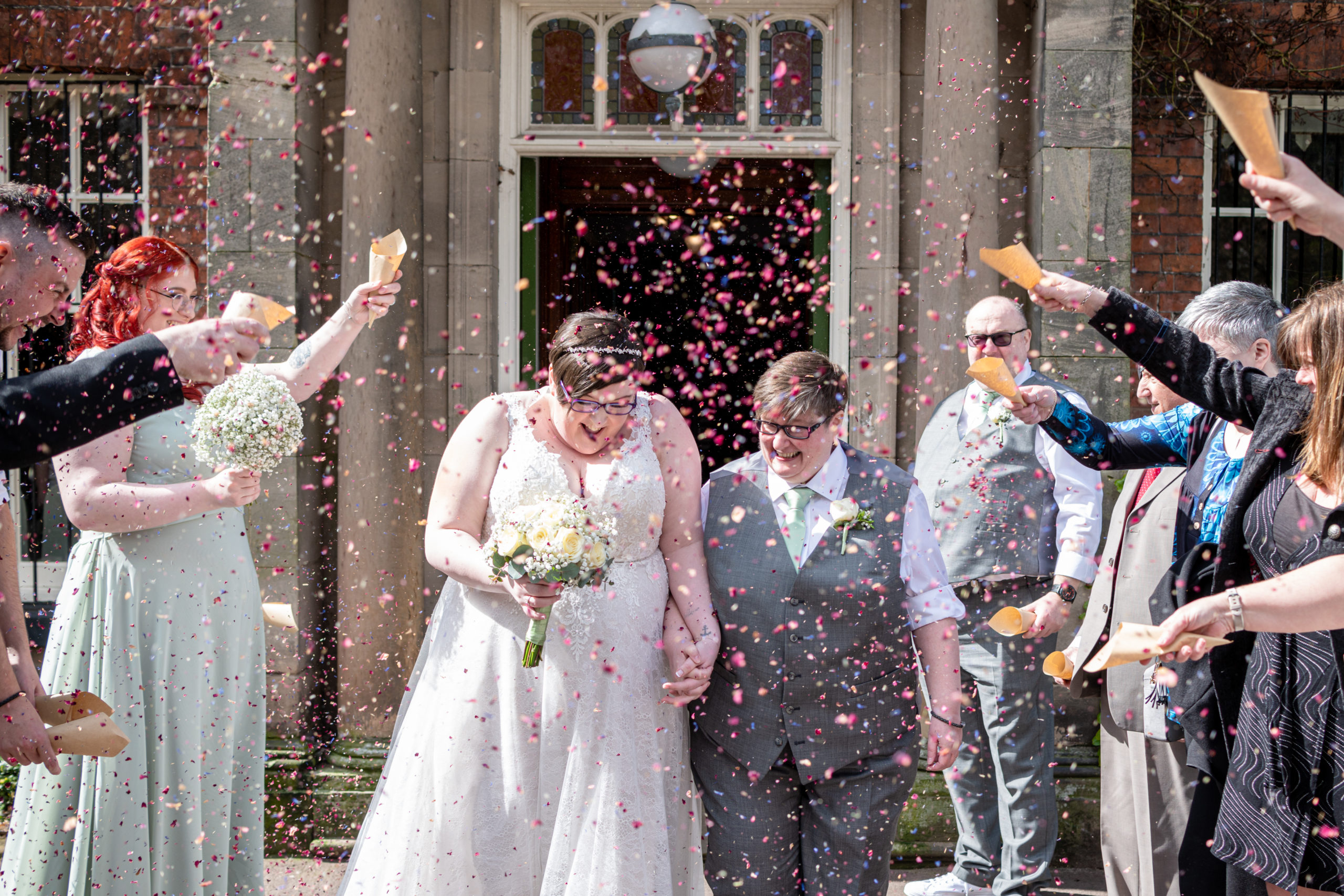 Same sex wedding confetti moment at Bantock House – Nat and Jane smiling as guests throw colourful confetti