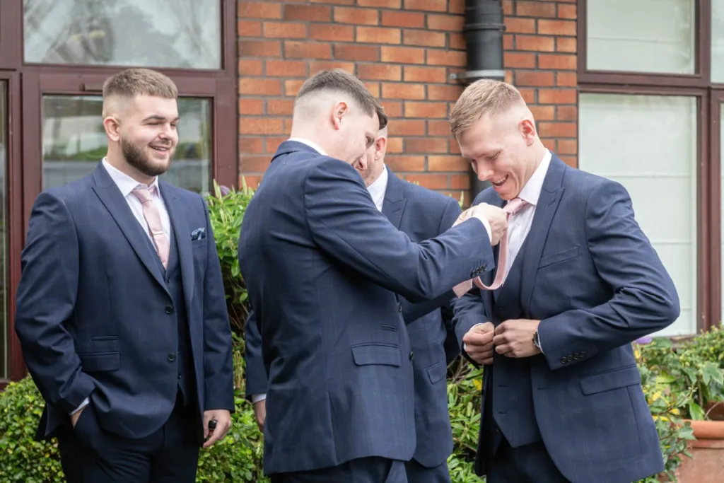 Ryan getting ready and sharing a light-hearted moment with loved ones ahead of the winter wedding at Draycote Hotel.