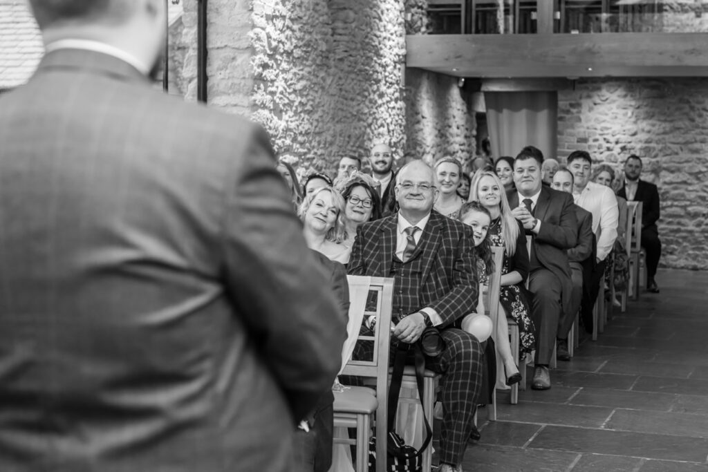 A diverse group of attendees seated in a stylish venue, smiling and engaged while listening to a speaker in the foreground.