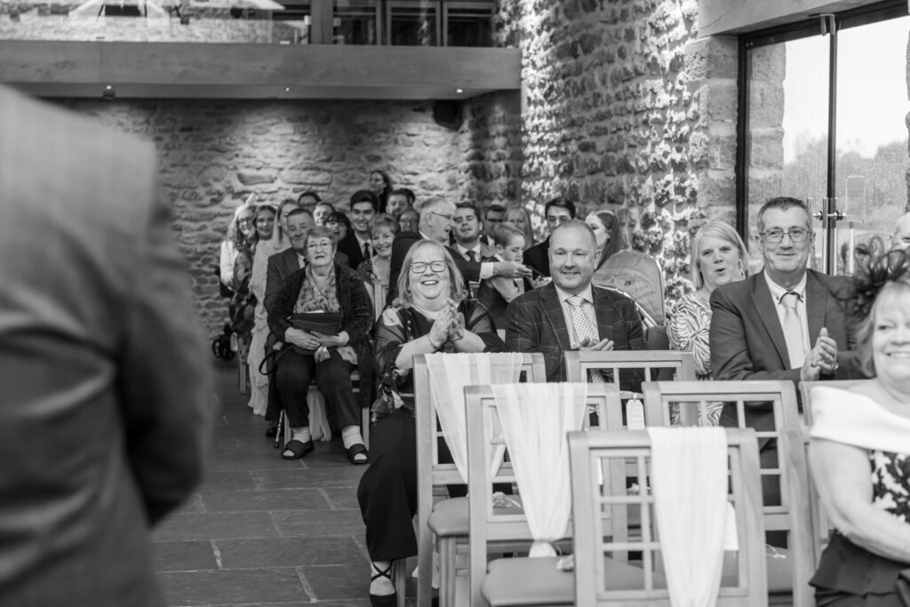 Guests applauding during a wedding ceremony in a beautifully lit venue.