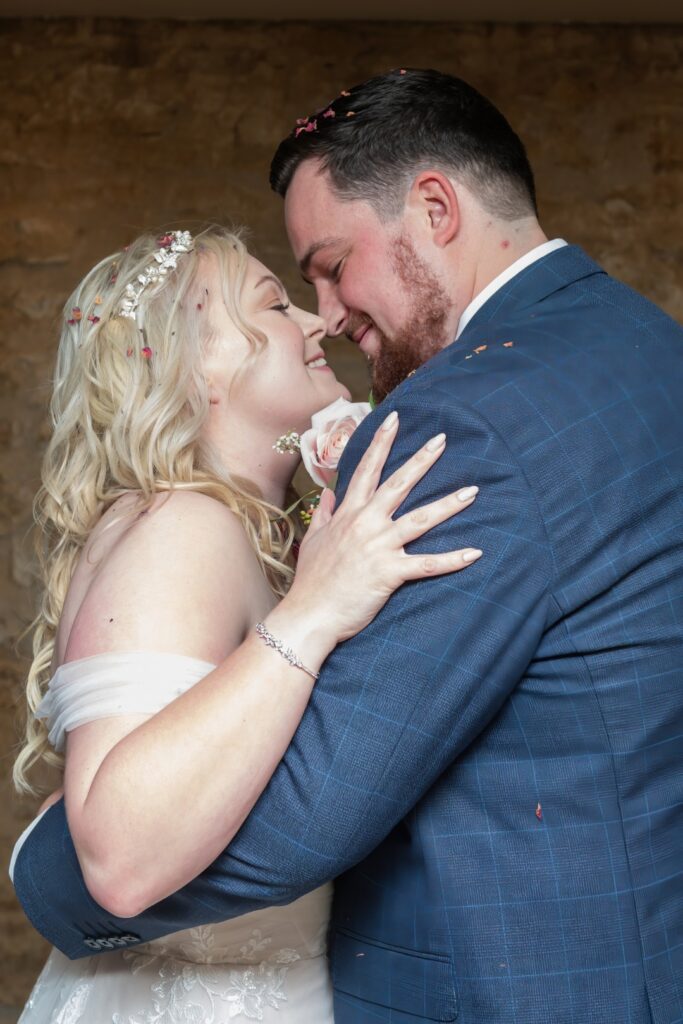A bride and groom embrace joyfully, surrounded by flower petals, showcasing love and happiness on their special day.