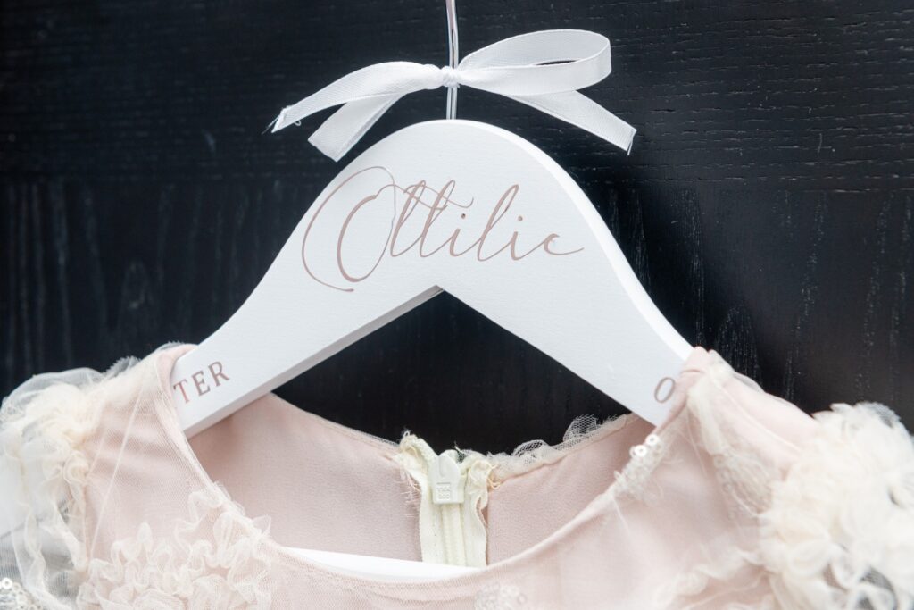 Close-up of a dress hanging on a white hanger with the name "Otilic" elegantly printed on it.