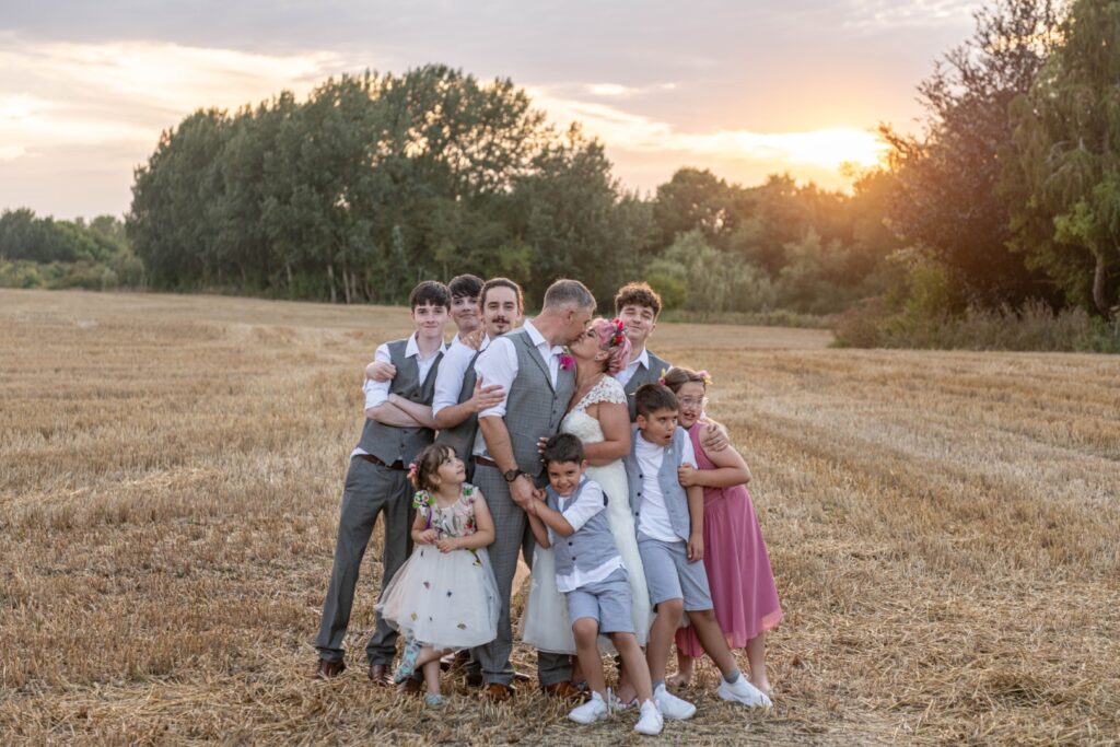 A joyful family poses together in an open field at sunset, showcasing love and togetherness.