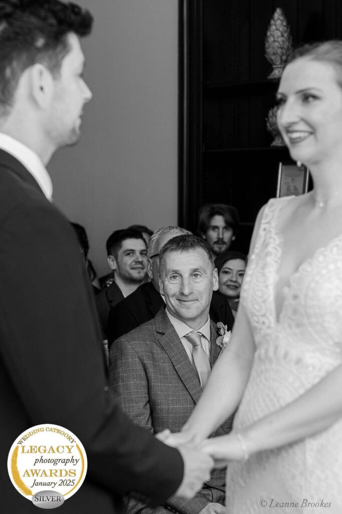 An emotional groom and bride exchanging vows, with a proud father figure witnessing the moment.