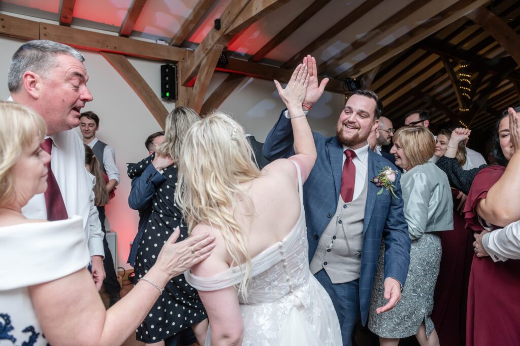 A joyful moment captured during a wedding reception, featuring guests dancing and interacting in a festive atmosphere.