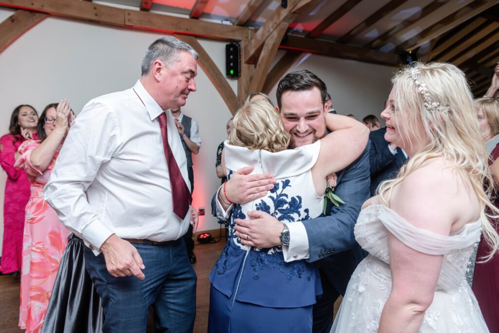 Guests sharing warm embraces and laughter during a lively event, creating memorable moments together.