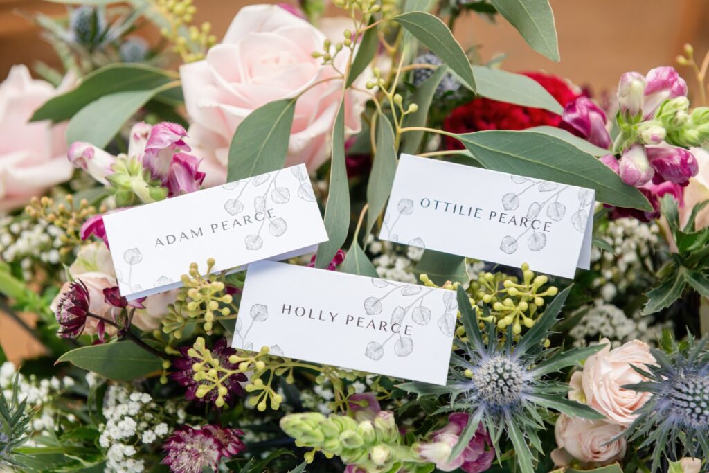 A close-up of a floral arrangement featuring elegant place cards with names written in a stylish font.