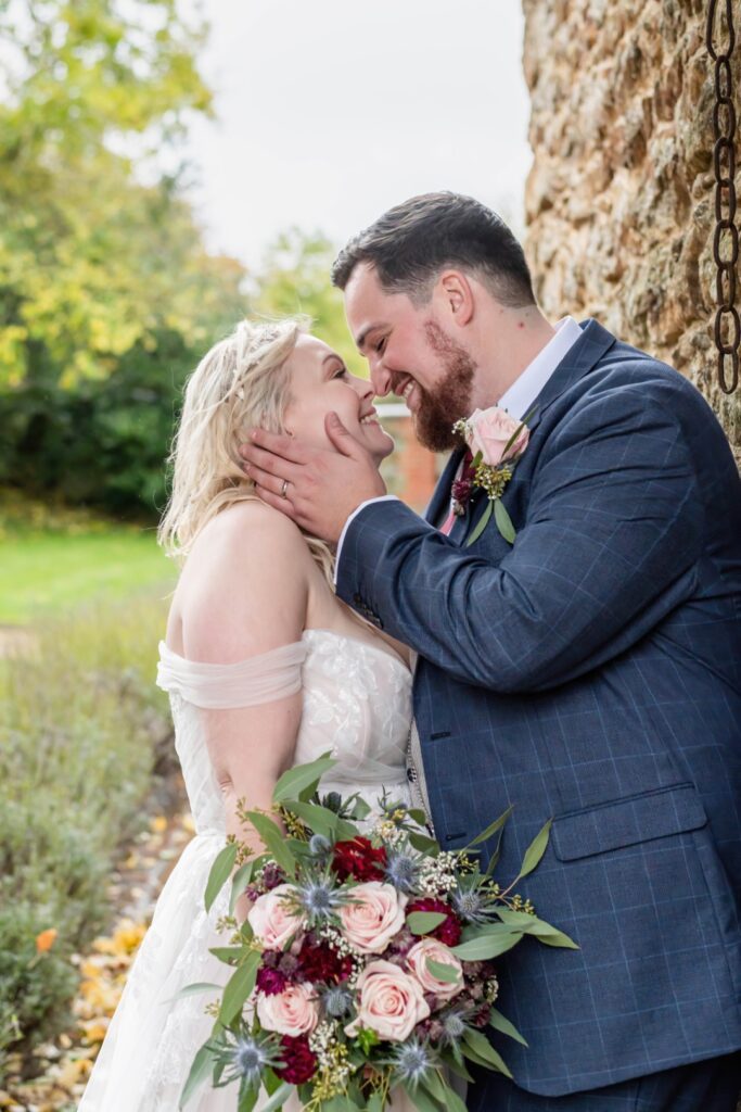 A joyful couple sharing an intimate moment, gazing into each other's eyes, surrounded by nature, with a beautiful bouquet in the bride's hands.