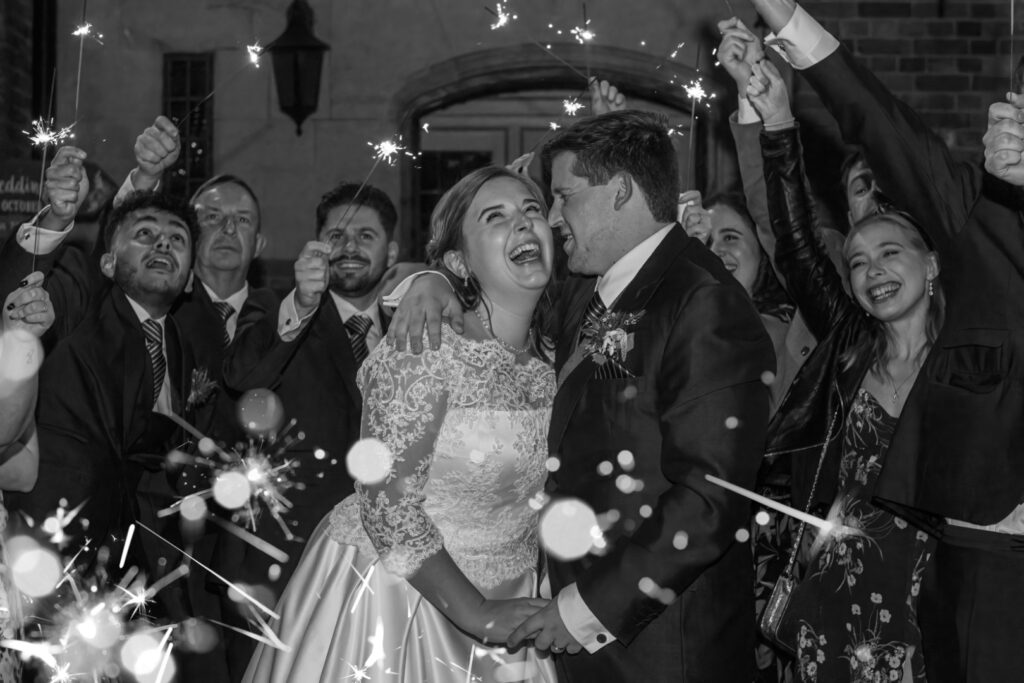 Couple laughing as they walk through a sparkler send-off with guests on both sides