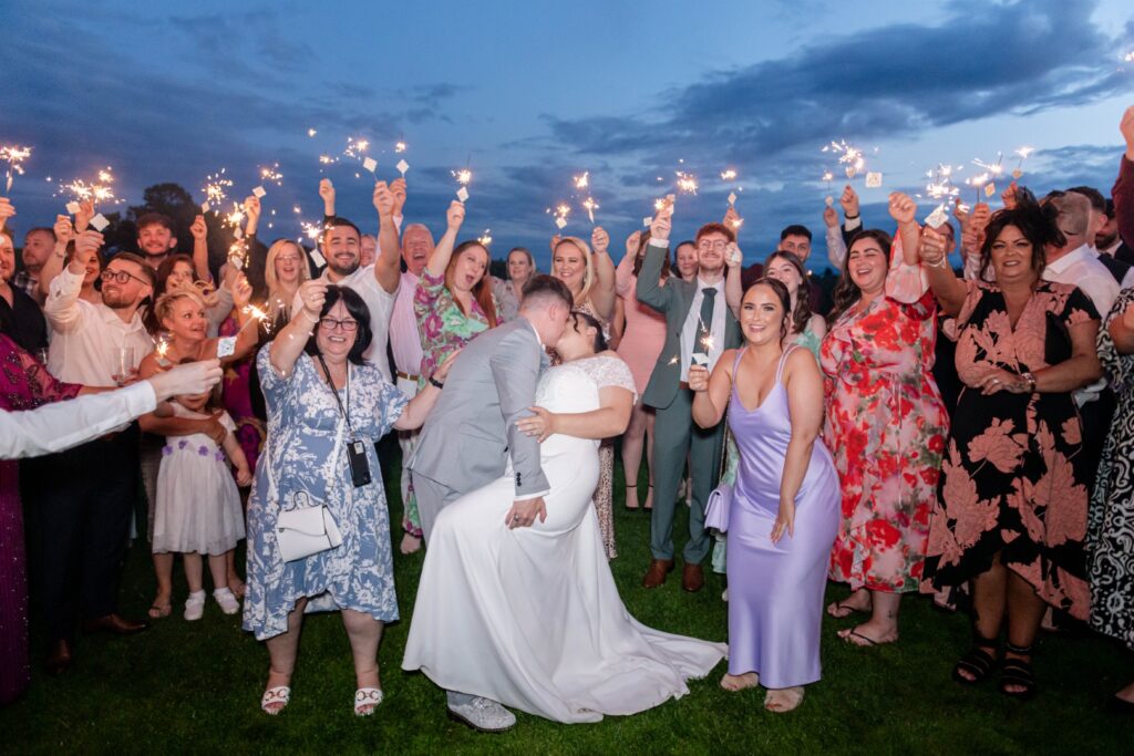 Bride and groom laugh together in the middle of joyful sparkler wedding photos