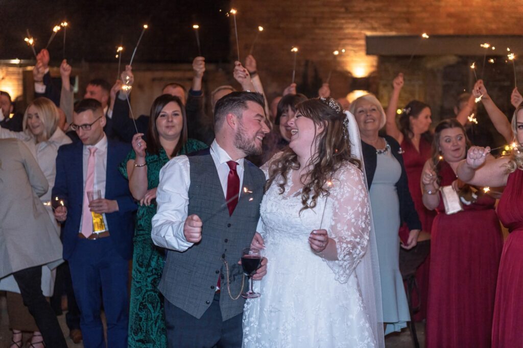 Sparkler wedding exit as couple share a laugh and hold sparklers together