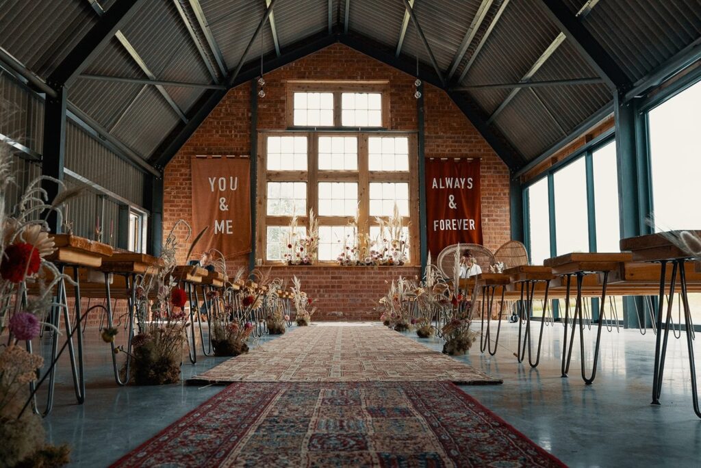 Unique wedding setup inside the Giraffe Shed, with bold banners and dried floral aisle decor in a quirky modern barn.