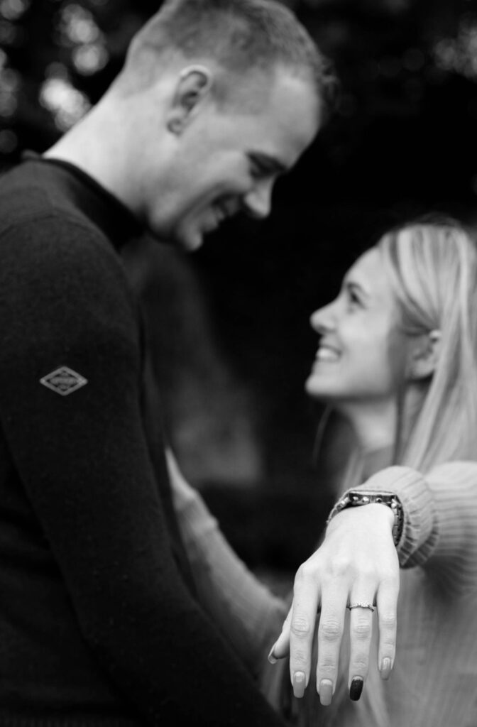 Couple smiling during engagement shoot with bride-to-be showing her ring – relaxed couples portfolio photography with candid connection