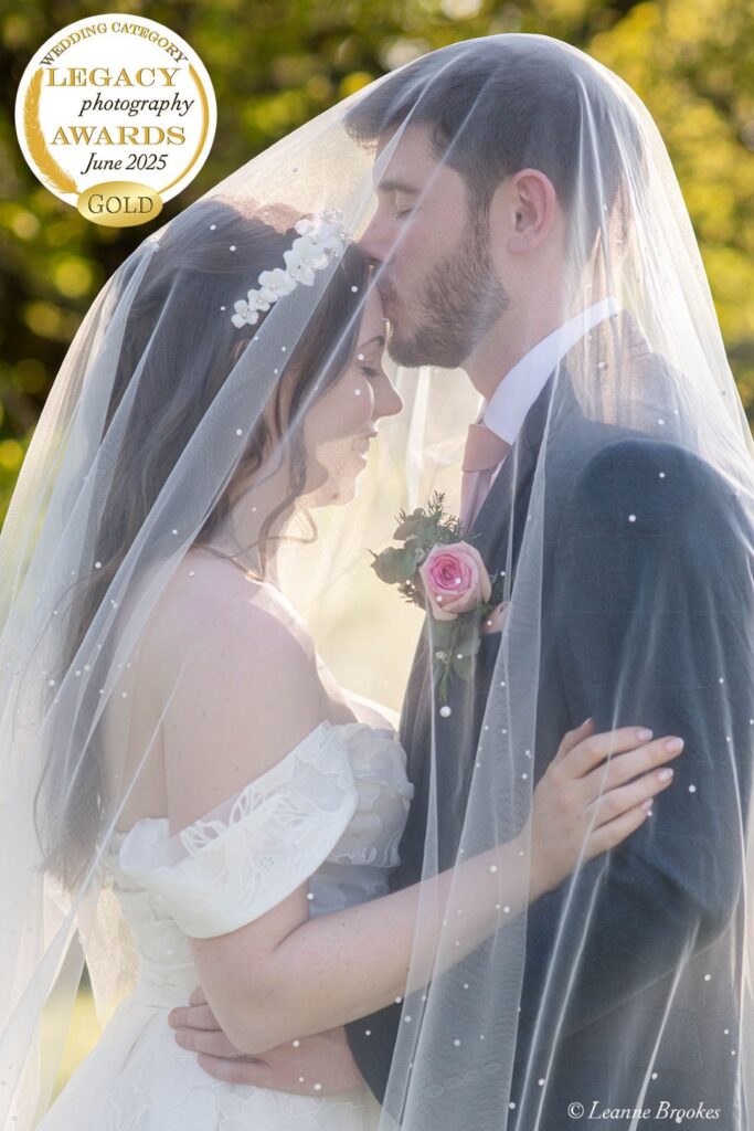 A couple embraces tenderly under a delicate veil, showcasing their love on a bright wedding day.