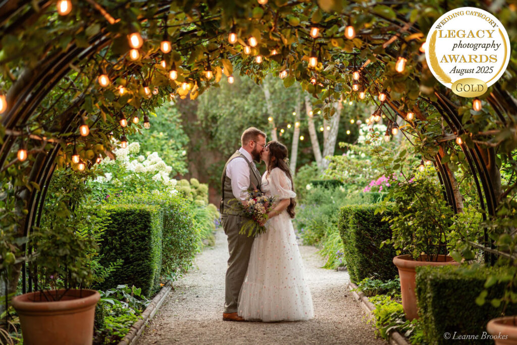 Wedding Photography Portfolio – award-winning golden hour kiss under garden arch with fairy lights