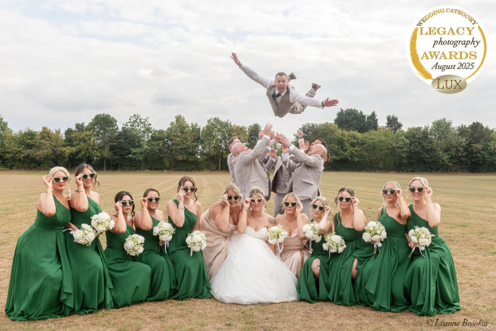 Wedding Photography Portfolio – fun bridal party portrait with bridesmaids in green dresses and groomsmen throwing the groom