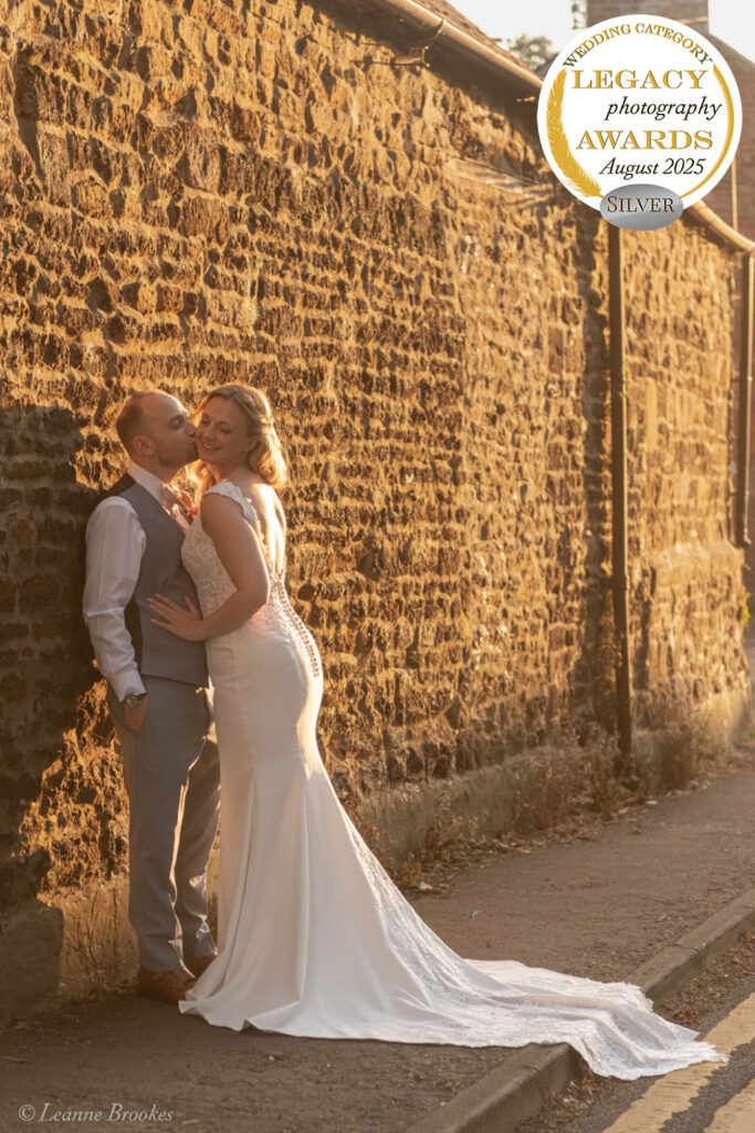 Wedding Photography Portfolio – romantic golden hour portrait of bride and groom against rustic stone wall