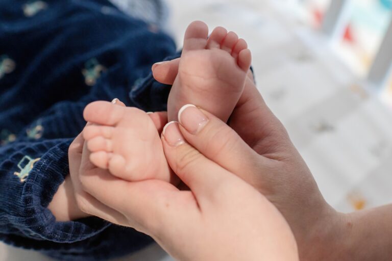 A close-up of a caregiver holding a baby's feet, showcasing delicate toes and soft skin, highlighting a moment of affection.