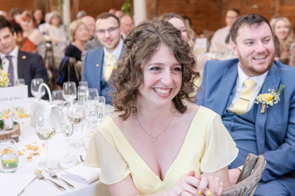 Natural wedding moment – guest in yellow dress smiling at reception, part of the magic of candid wedding photos