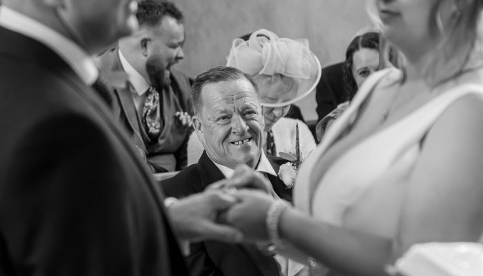 Joyful candid wedding photo of a guest embracing someone during the ceremony – capturing the magic of real moments